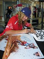 Ashley Fiolek signs photographs of herself as she represents her Honda Racing team. Photo courtesy of Gerald Geronimo.