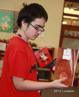 Ninth grader, Kyle Roberts examines the books that he is purchasing at the Book Fair. He bought the books to support Scholastic.
Photo By: Hanna Feathers