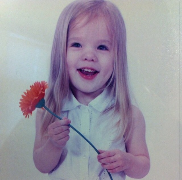 Ninth grader Anna DeRubeis poses with a flower while getting professional pictures taken.  DeRubeis was three years old when this photo was taken.
