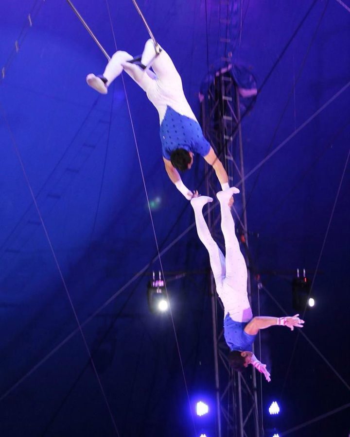 Alex Cortes hangs upside down with his partner in the midst of performing. 