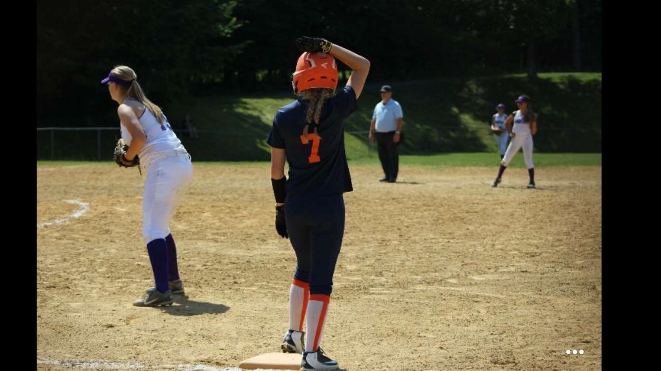 Riley Steinbugl waits on base while the pitcher throws the ball. She is getting ready to take a lead.