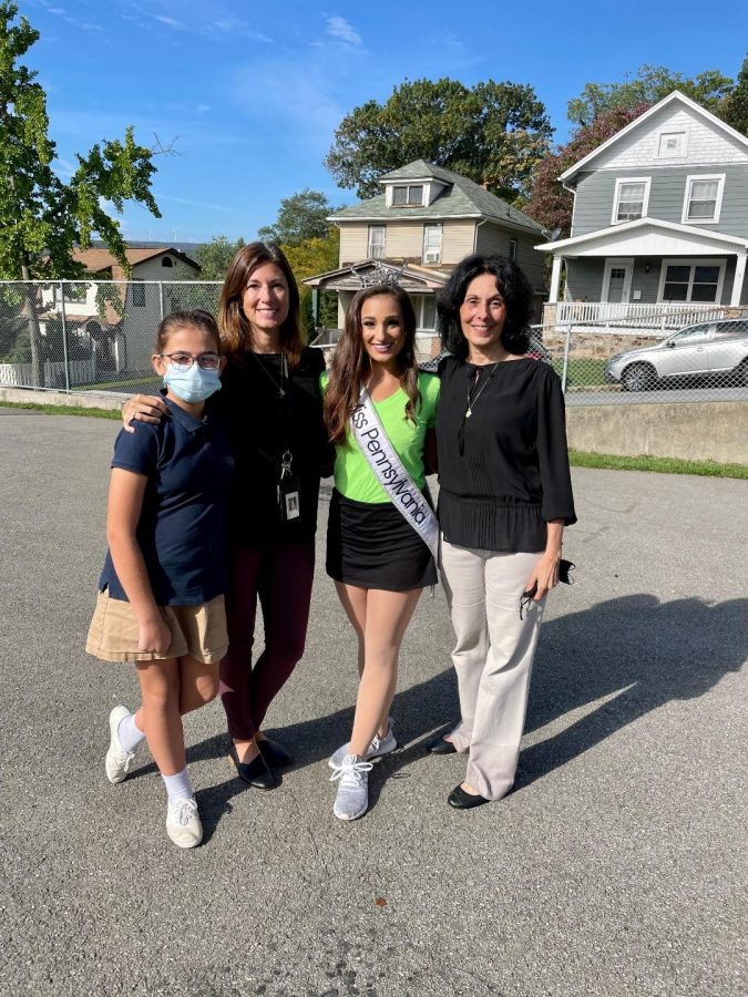 At McAuliffe Heights Elementary School, Brynn Plunket, Michele Plunket, Meghan Sinisi and Patty Watson pose for a photo after Sinisi performed and spoke to students.  