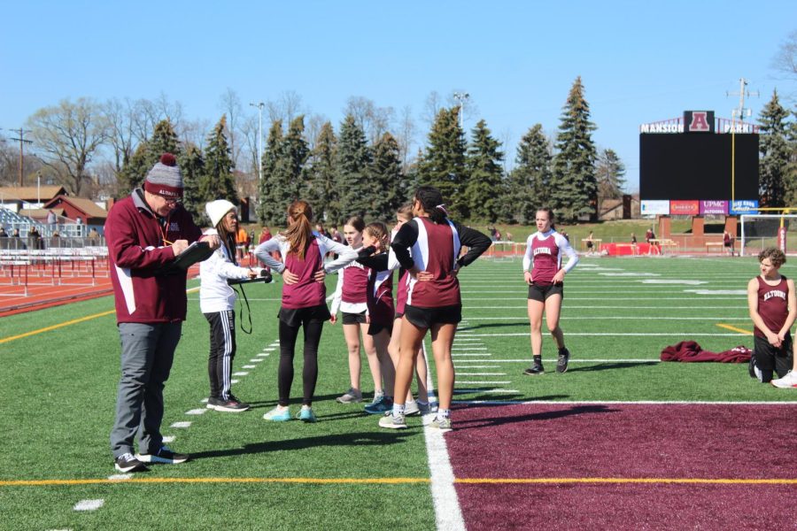 The seventh and eighth grade girls talk to their distance coach after finishing their 4 by 800 relay race. 
