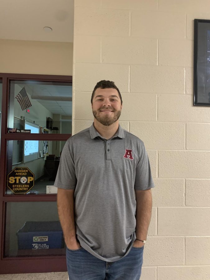 Pose! Eighth grade history teacher Dominic Williams poses for a picture outside his classroom. He had been teaching a class beforehand, engaging with his students.
