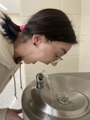 Wrong! Eighth grade student Giuliana Miller shows how students should not drink from the water fountain. Students should not put their whole mouth on the faucet because that is the wrong way to drink from the fountains. 