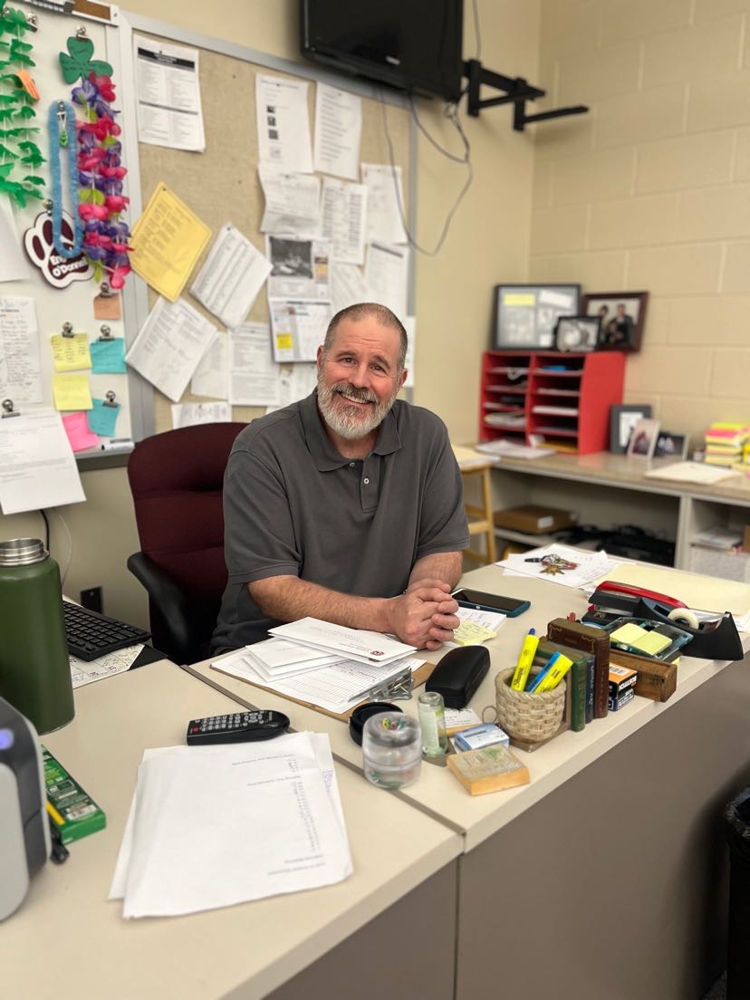 Farewell! Jim ODonnell poses for the last at his desk he wont be sitting at next year.  He loved to teach students from his advanced perspective of an elder.