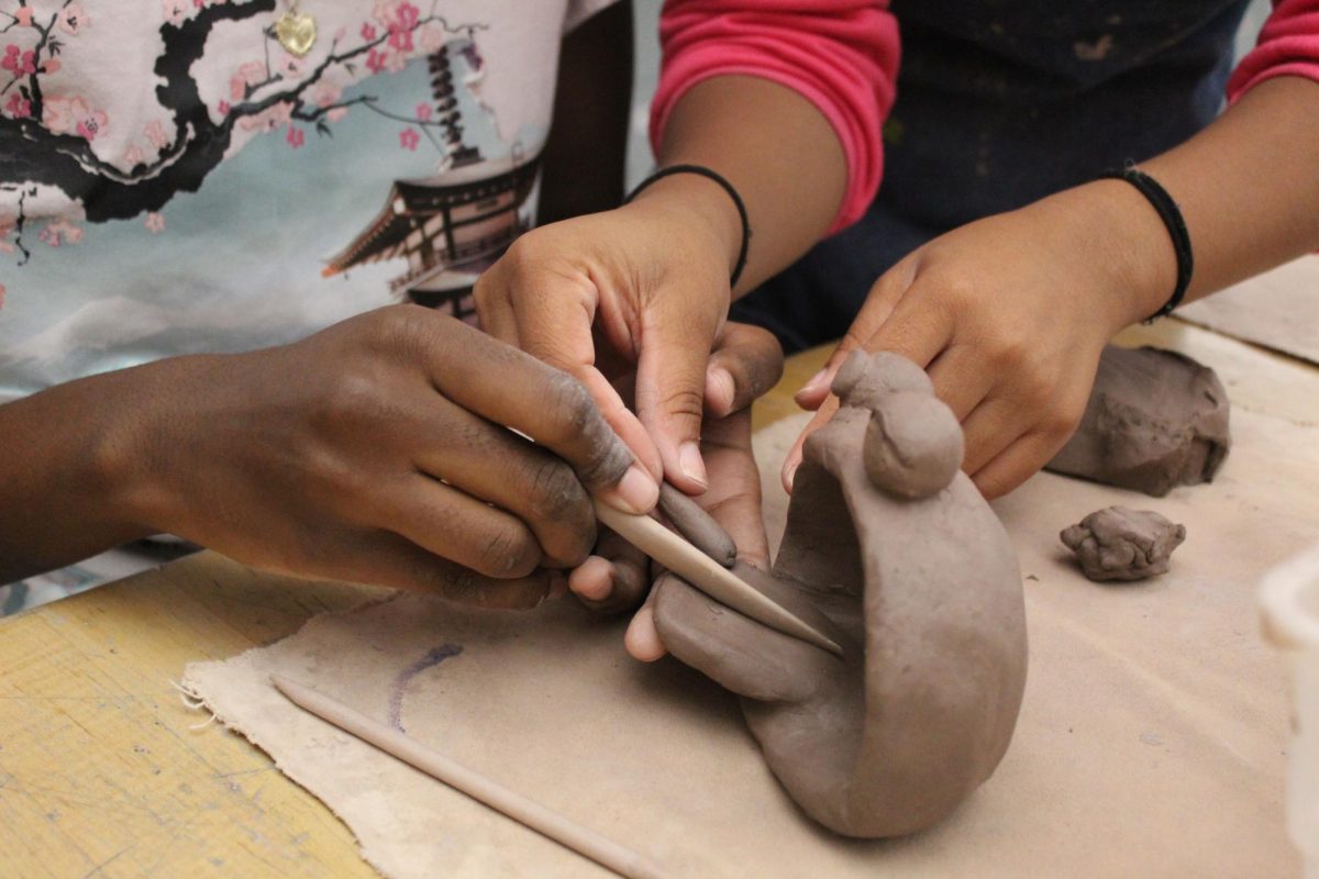 Yum, yum! Two girls help each other complete their monster pot. They are designing the Cookie Monster. 