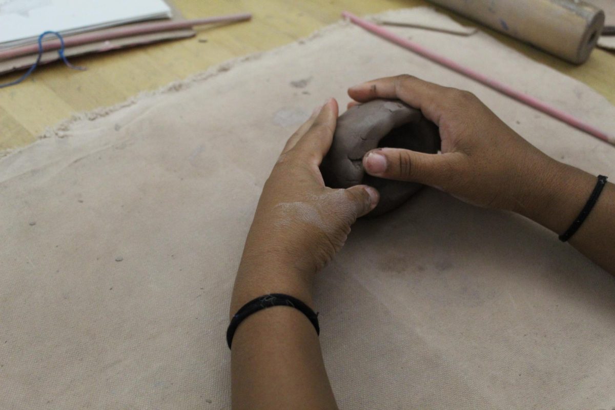 Smooth those edges! Eight grader Jackson is smoothing out her edges on her monster pot. She does this so that her pot doesn't come out with sharp edges.