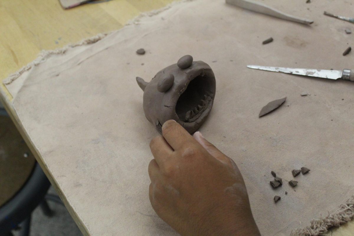 Scratch and attach! Eight grader Jackson is scratching and attaching her teeth to her shark. You have to use a sharp tool to scratch the sides. Then, put mud on it, so it will stay together.